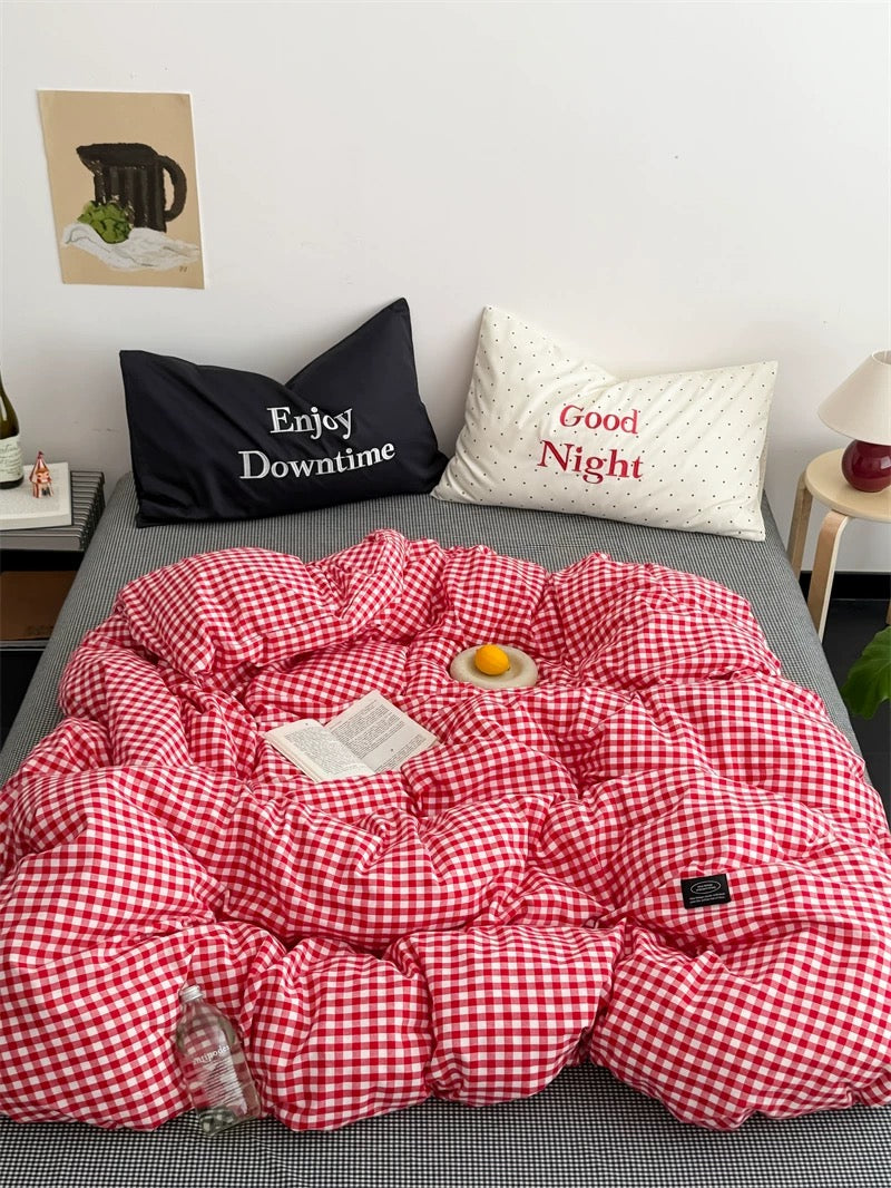 Red and white checkered comforter on a bed with pillows labeled 'Enjoy Downtime' and 'Good Night'.