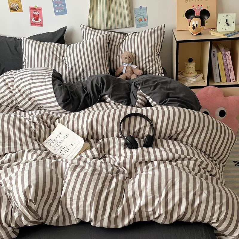 Minimalist black striped duvet cover styled with grey rug and plush accessories
