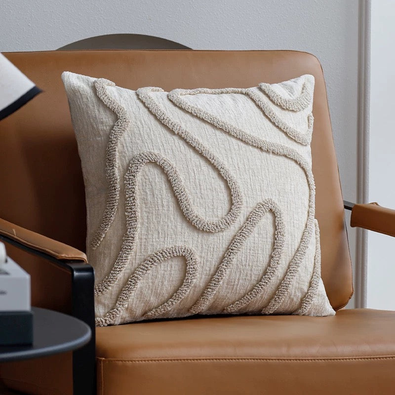 Textured beige pillow on a brown chair with a neutral background