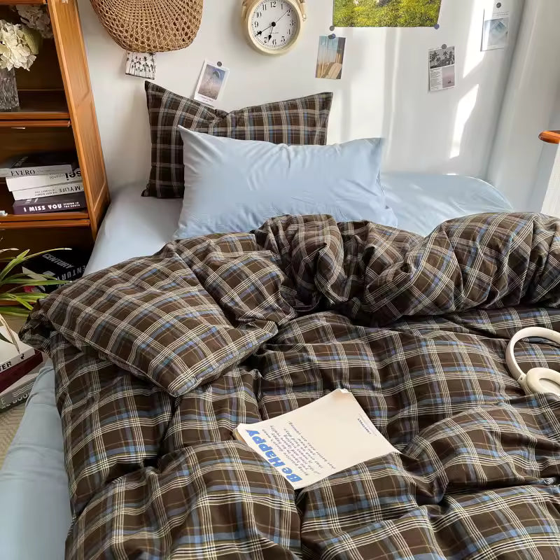 Bed with plaid comforter and pillows in a room with books and decor.
