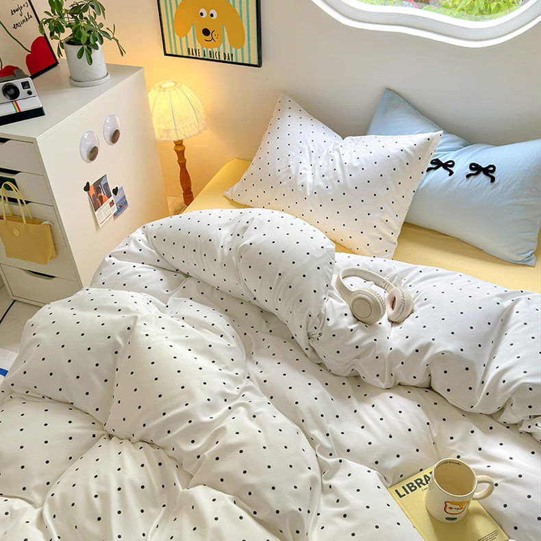 Cozy bed with yellow sheets and white polka dot duvet for dopamine bedroom