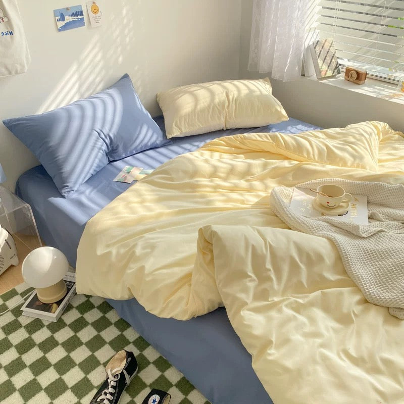 Aesthetic Korean bedding set in soft pastel tones of cream and blue, styled with a cozy blanket.