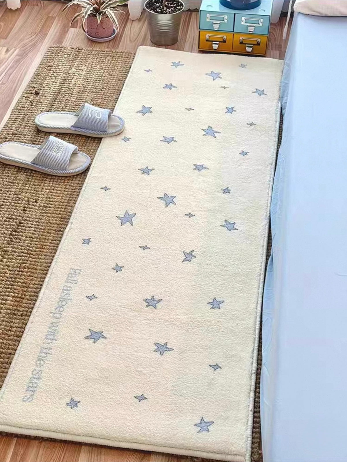 A cream and blue star runner lies beside a blue bed, with its rectangular outline visible from above.