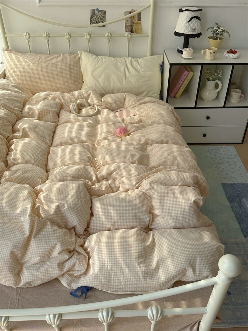 Neatly made bed with beige comforter in a bedroom setting.