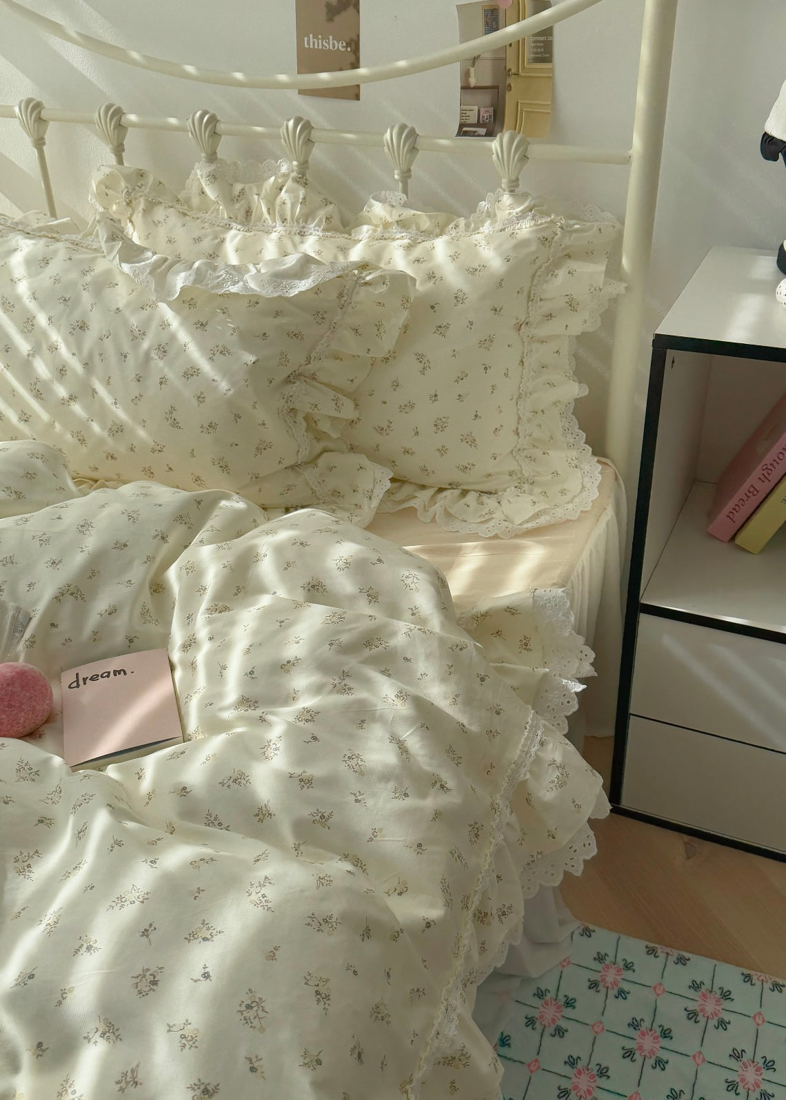 White floral bedding on a bed with a nightstand in the background