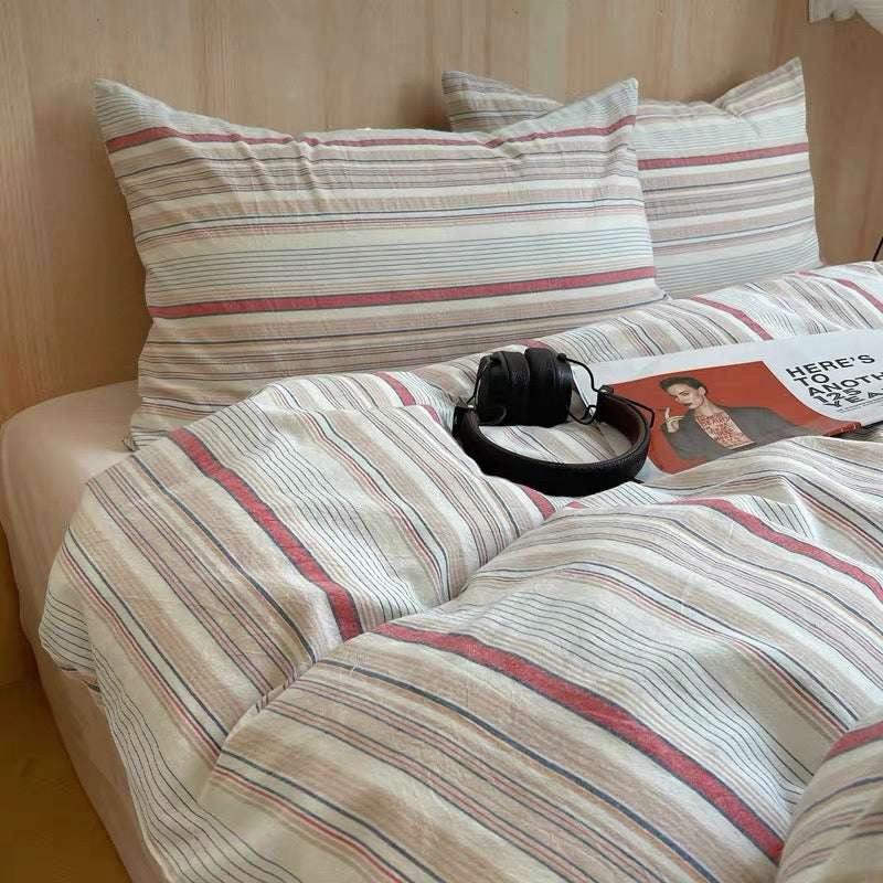 Striped bedding with a pillow and headphones on a bed.