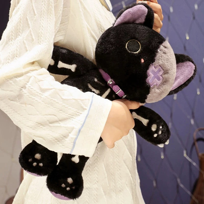 Black and gray plush toy with purple accents held by a person wearing a white robe.