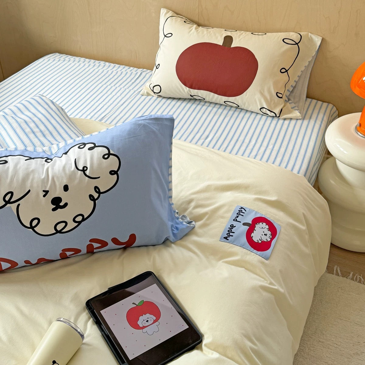 Bed featuring red apple-shaped pillow and soft cream duvet cover