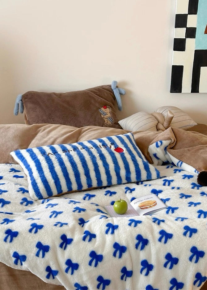 Bed with blue and white striped pillow, brown blanket, and checkered wall art.