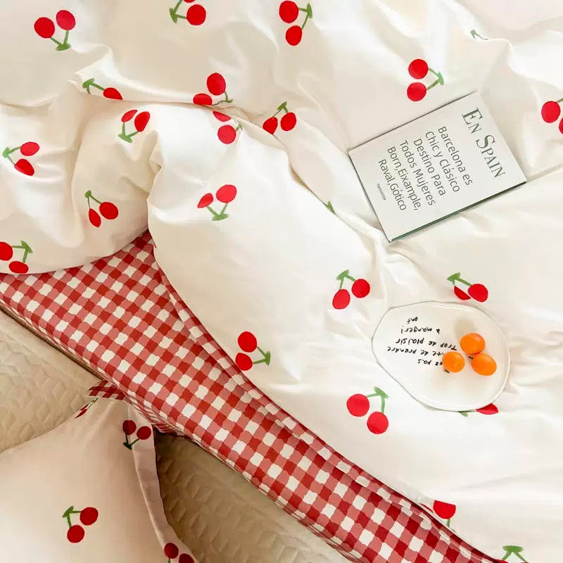Playful cherry bedding with red cherries on white duvet and pillowcases.