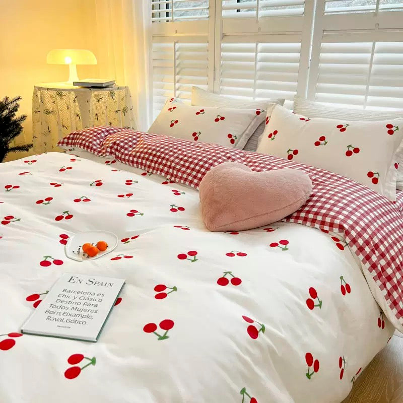 Cherry print bedding set styled with cozy pillows and gingham check accents.