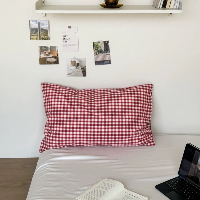 Cute cherry print pillowcase on a white bed styled with fairy lights and plush toys.