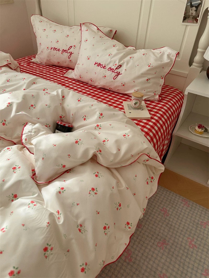 Floral and checkered bedding set on a bed with matching pillows.