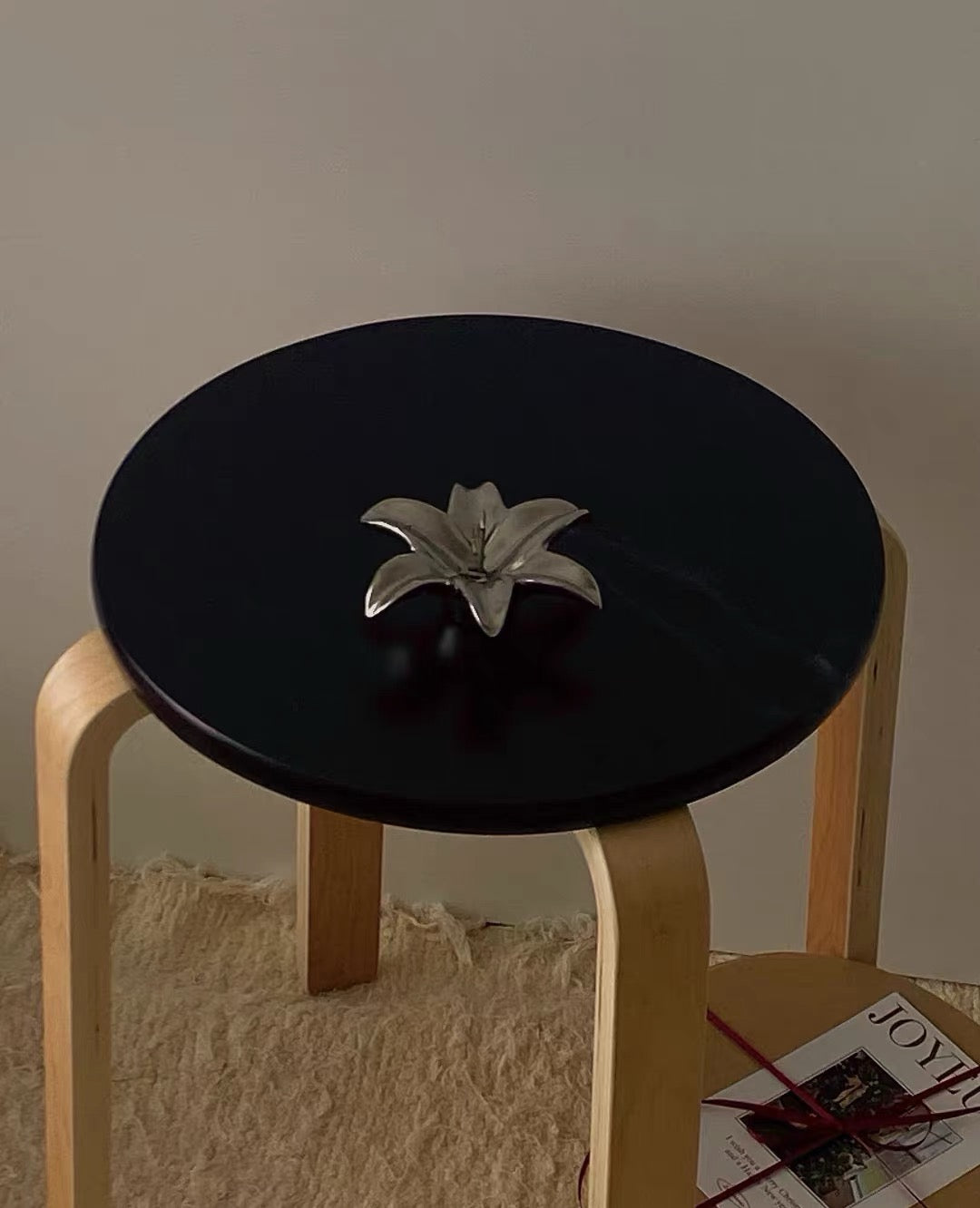 Small black round table with a decorative item on a neutral background