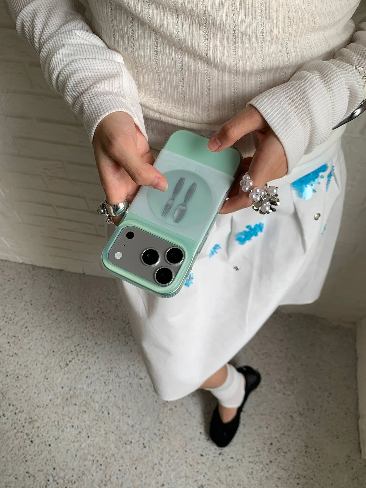 A cute Korean phone case in mint green, seen from above with the plate and cutlery design facing out.
