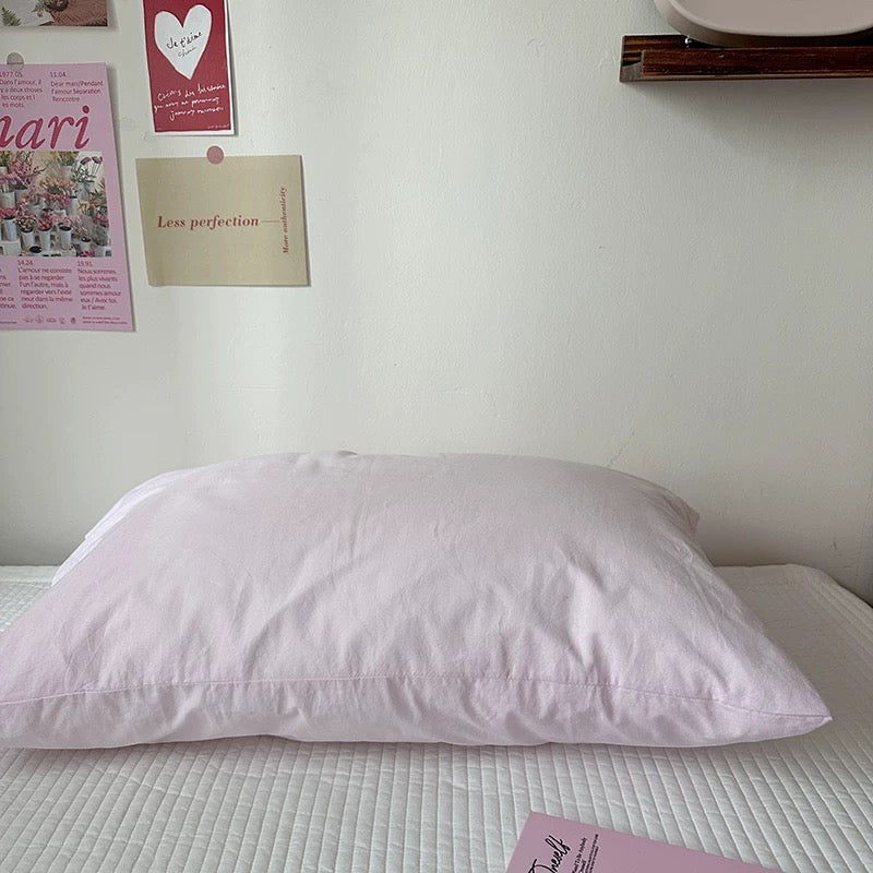 Pink pillow on a bed with posters on the wall