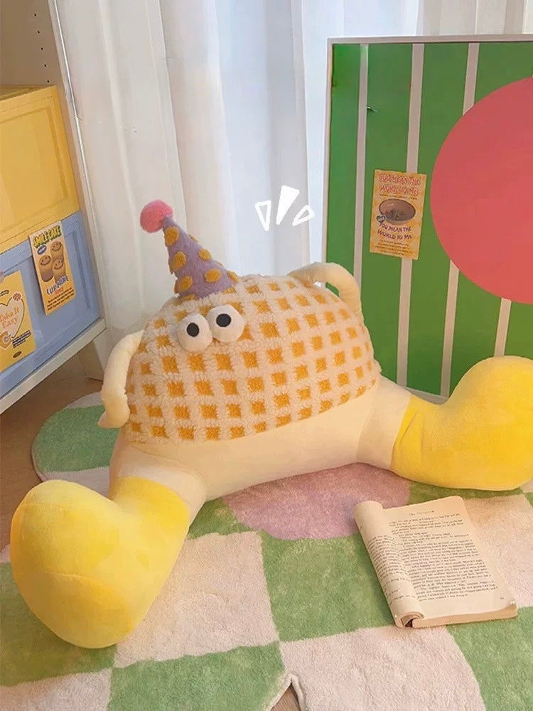Yellow plush toy with a checkered pattern and a party hat on a checkered floor.