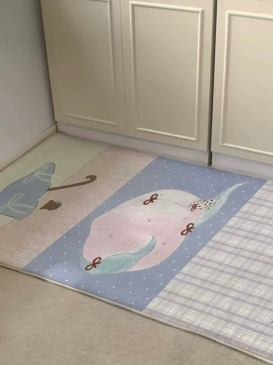 A bedside runner rug in lilac, pink and cream lies beside a bed, with a peach panel and checked section.