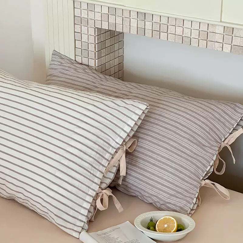 Blue striped cotton pillow sham with bow detail, perfect for cozy bed styling.