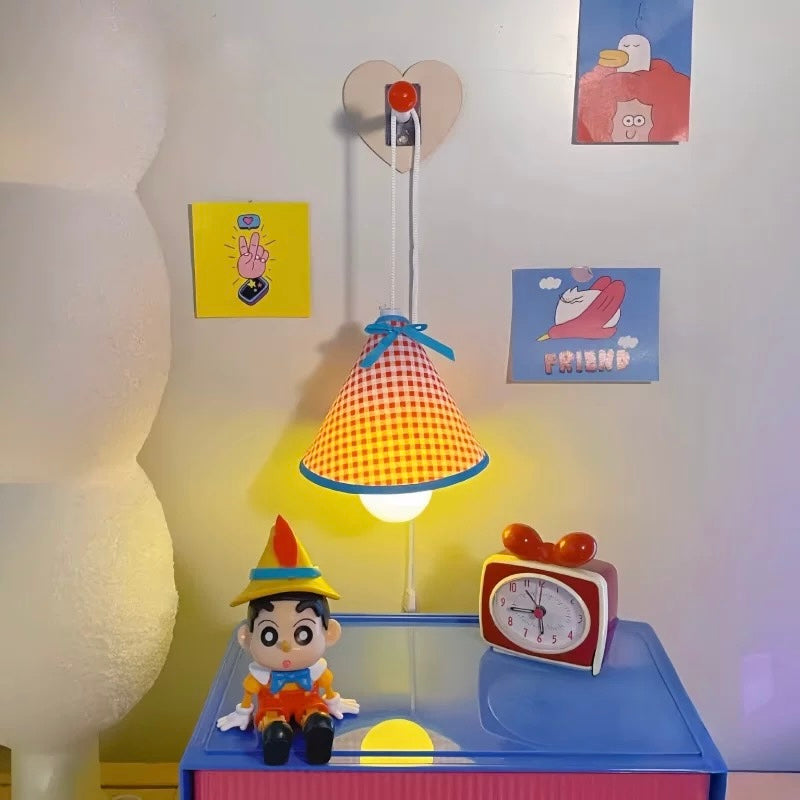 Children's lamp with checkered shade, clock, and figurine on a table against a wall with posters.