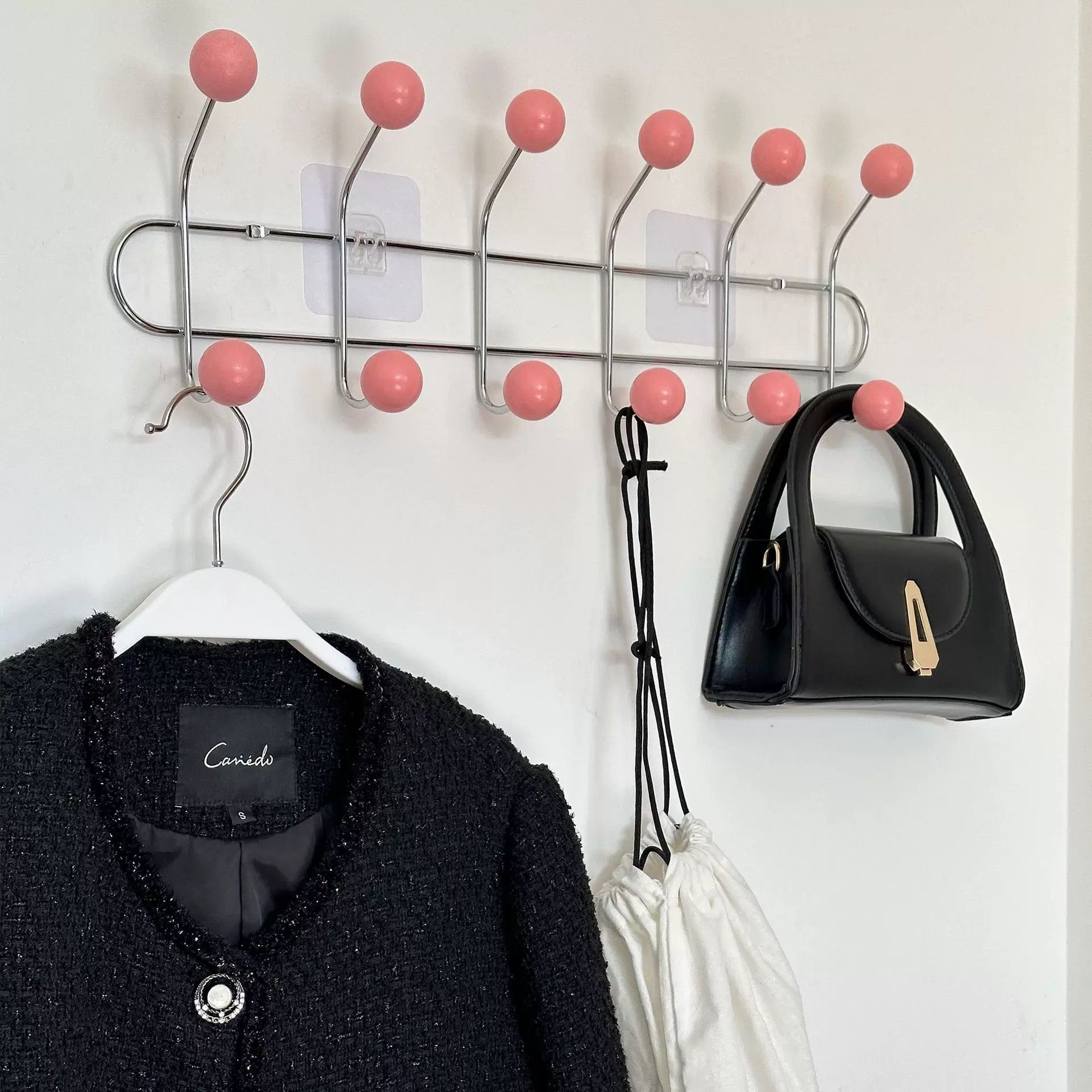 Wall mounted storage rack in pink for coats, towels, and hats