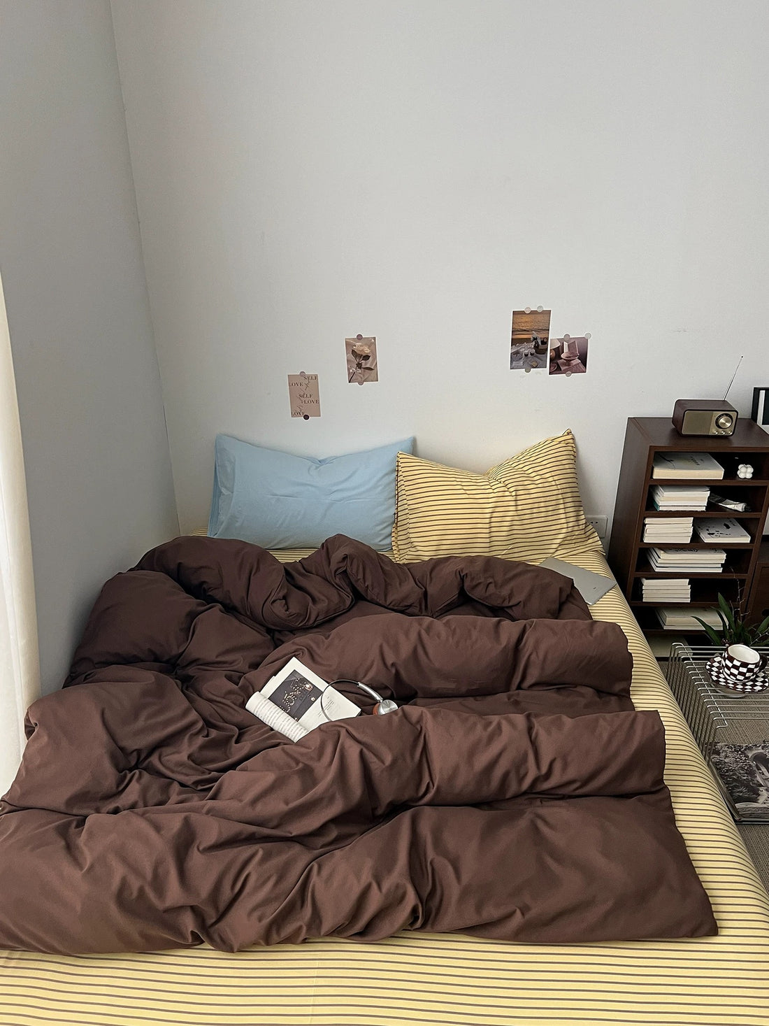 Dark brown bedding set with brown duvet cover, striped flat sheet, pale blue pillowcase and striped pillowcase