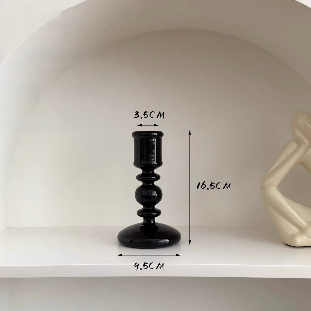 Black candle holder with measurements on a white shelf