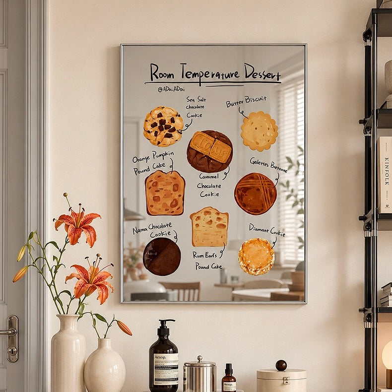 A framed wall art print featuring a whimsical dessert-themed poster titled 'Room Temperature Dessert' hangs on a beige wall in a styled room. The poster shows illustrated baked goods like cookies, cakes, and pastries with handwritten labels.