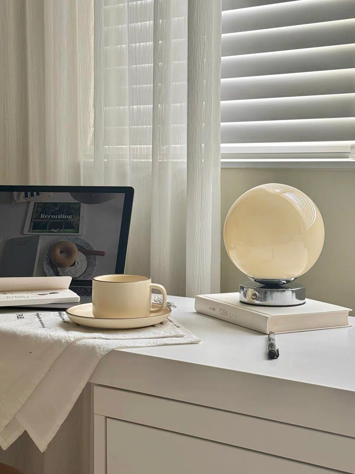 Desk setup with laptop, mug, and decorative sphere in a home office.