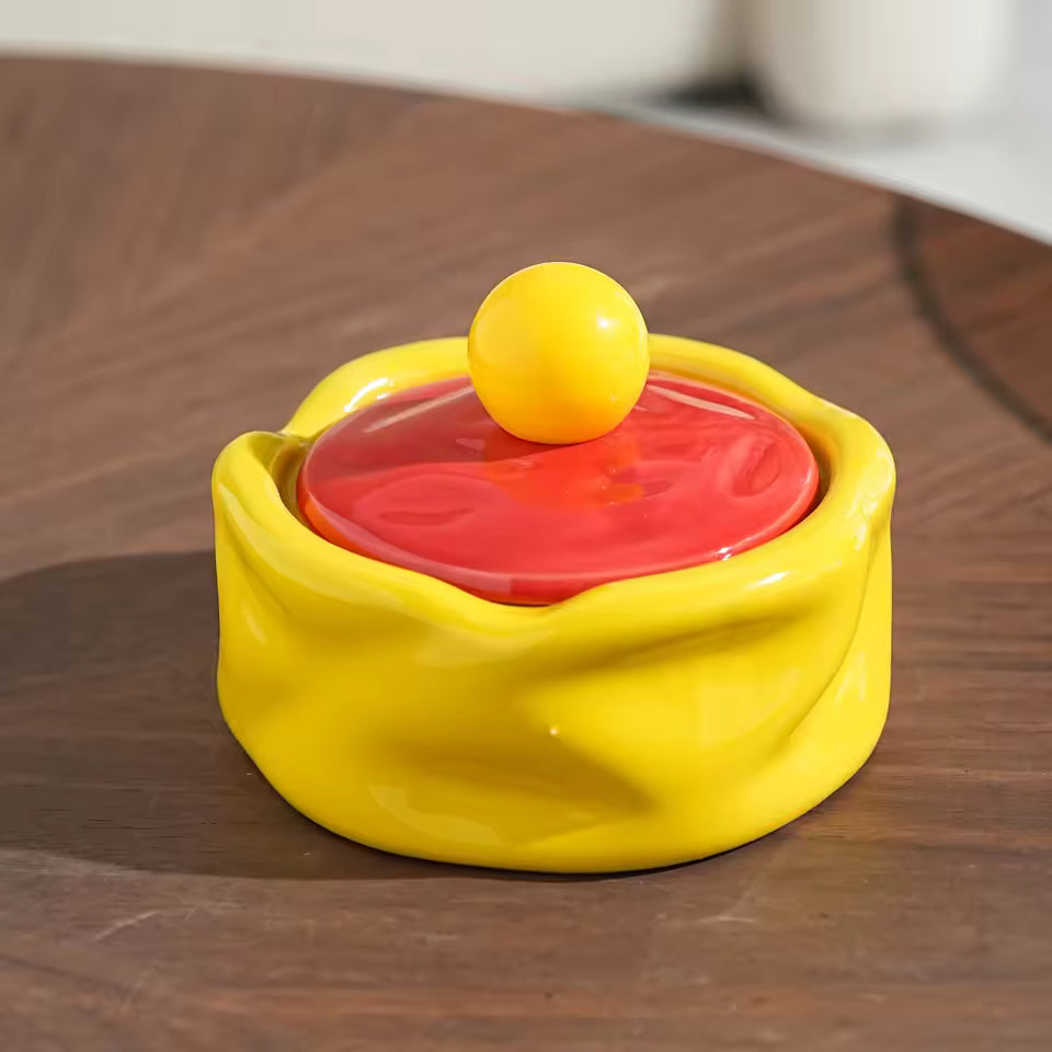 Yellow and red ceramic dish with a yellow ball on a wooden surface