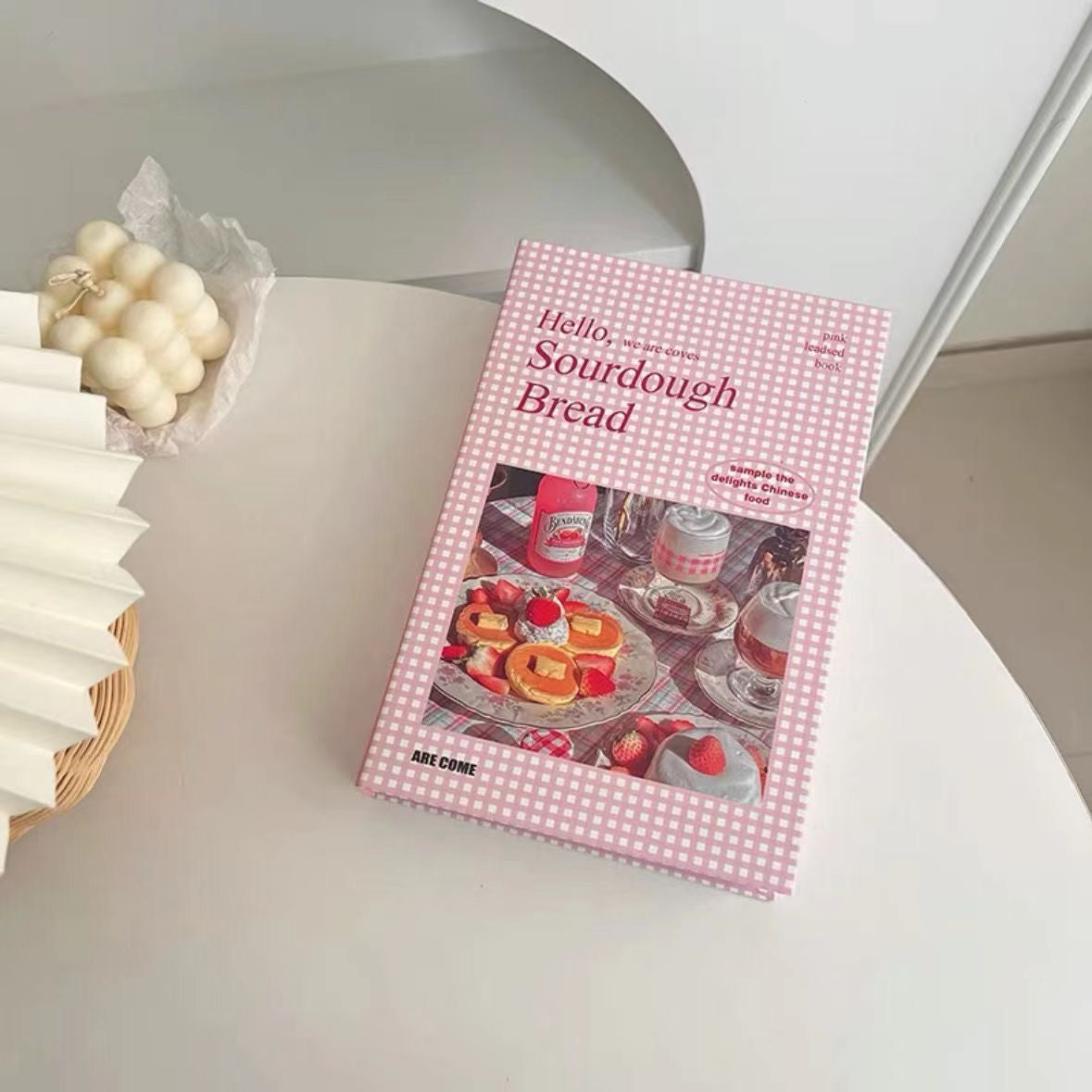 Book titled 'Hello Sourdough Bread' on a white surface with a decorative item in the background.