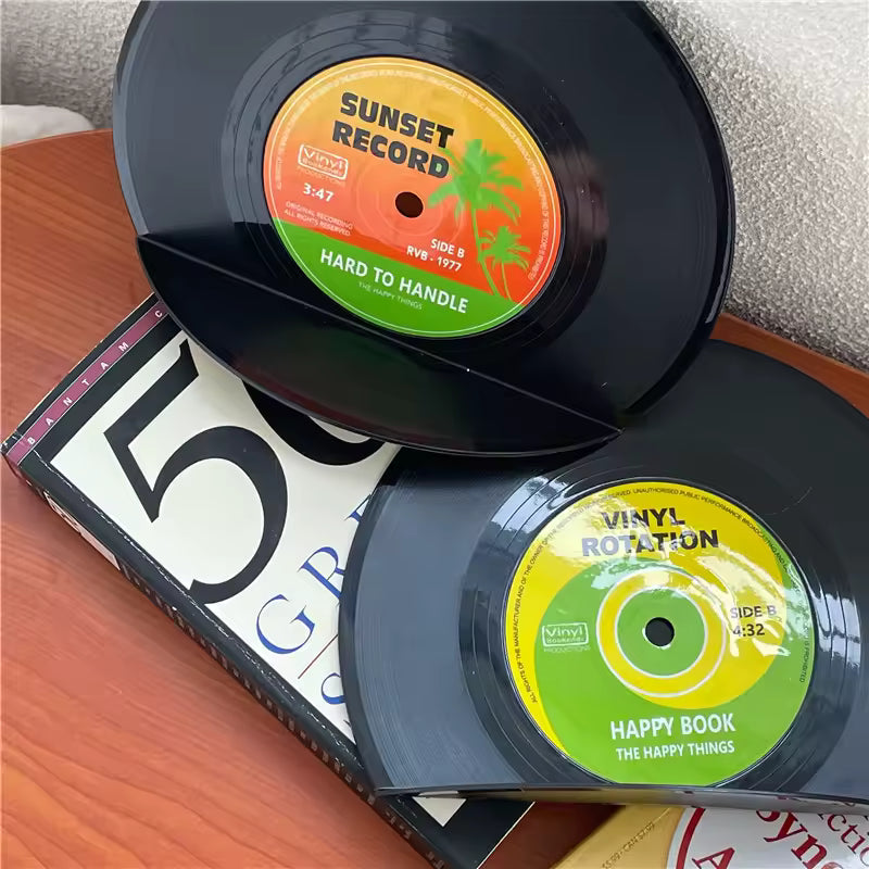 Two vinyl records with colorful labels on a wooden surface.