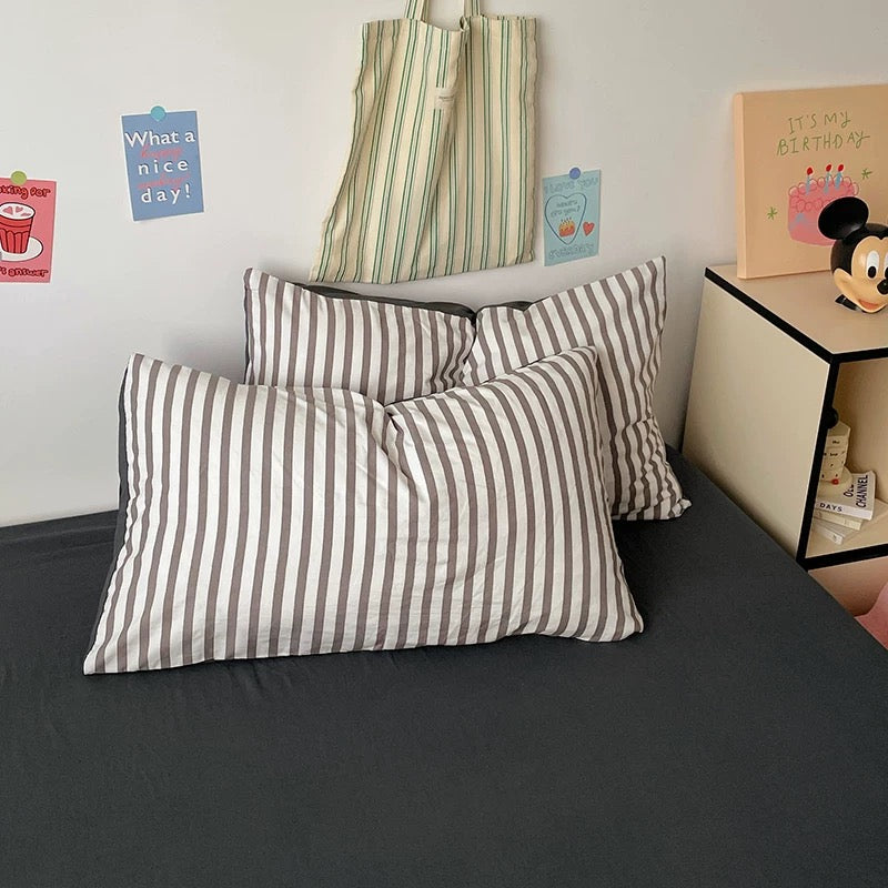Striped pillows on a bed with a nightstand and decorative items in the background