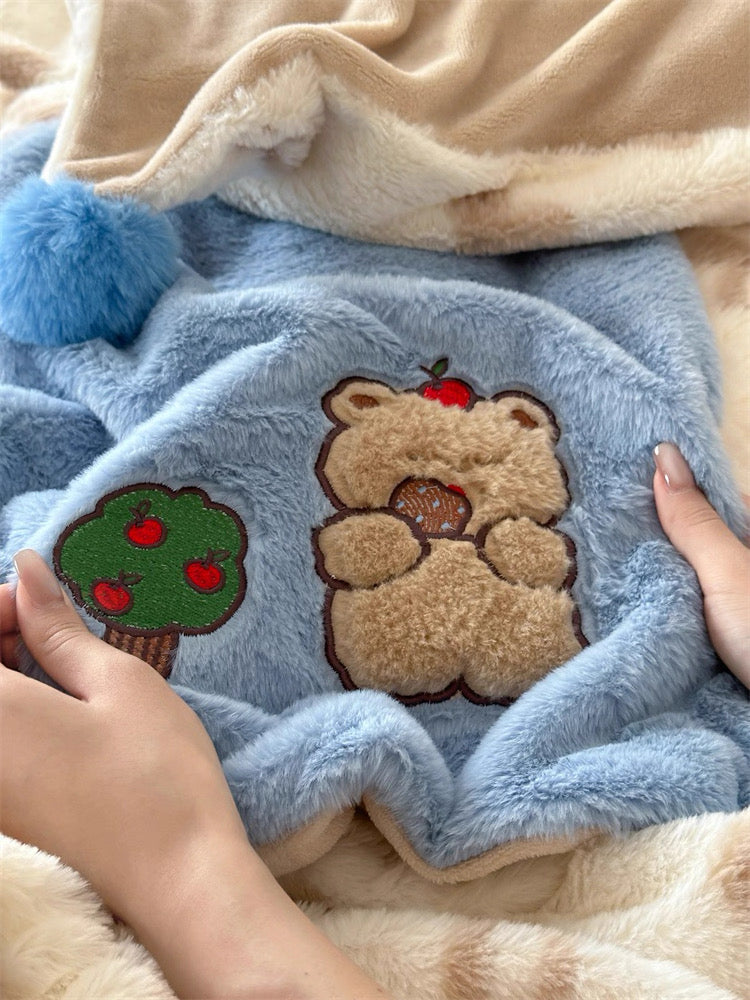 Blue blanket with teddy bear and apple tree patch held by a person