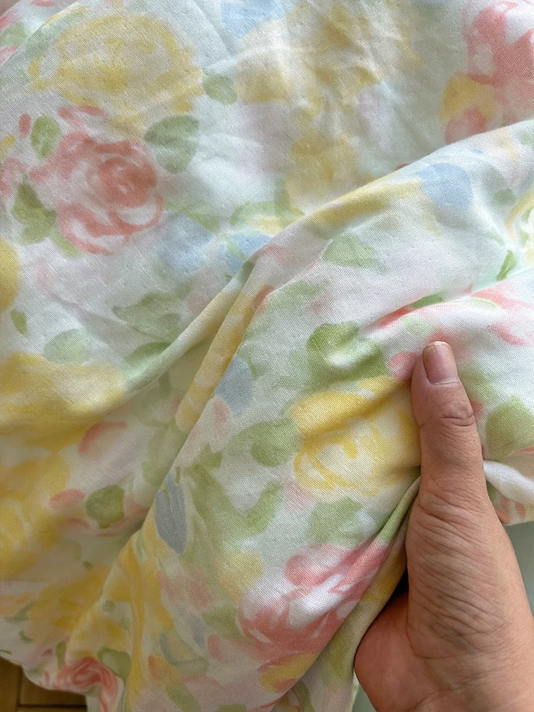 Close-up of the printed cotton gauze bedding held between fingers