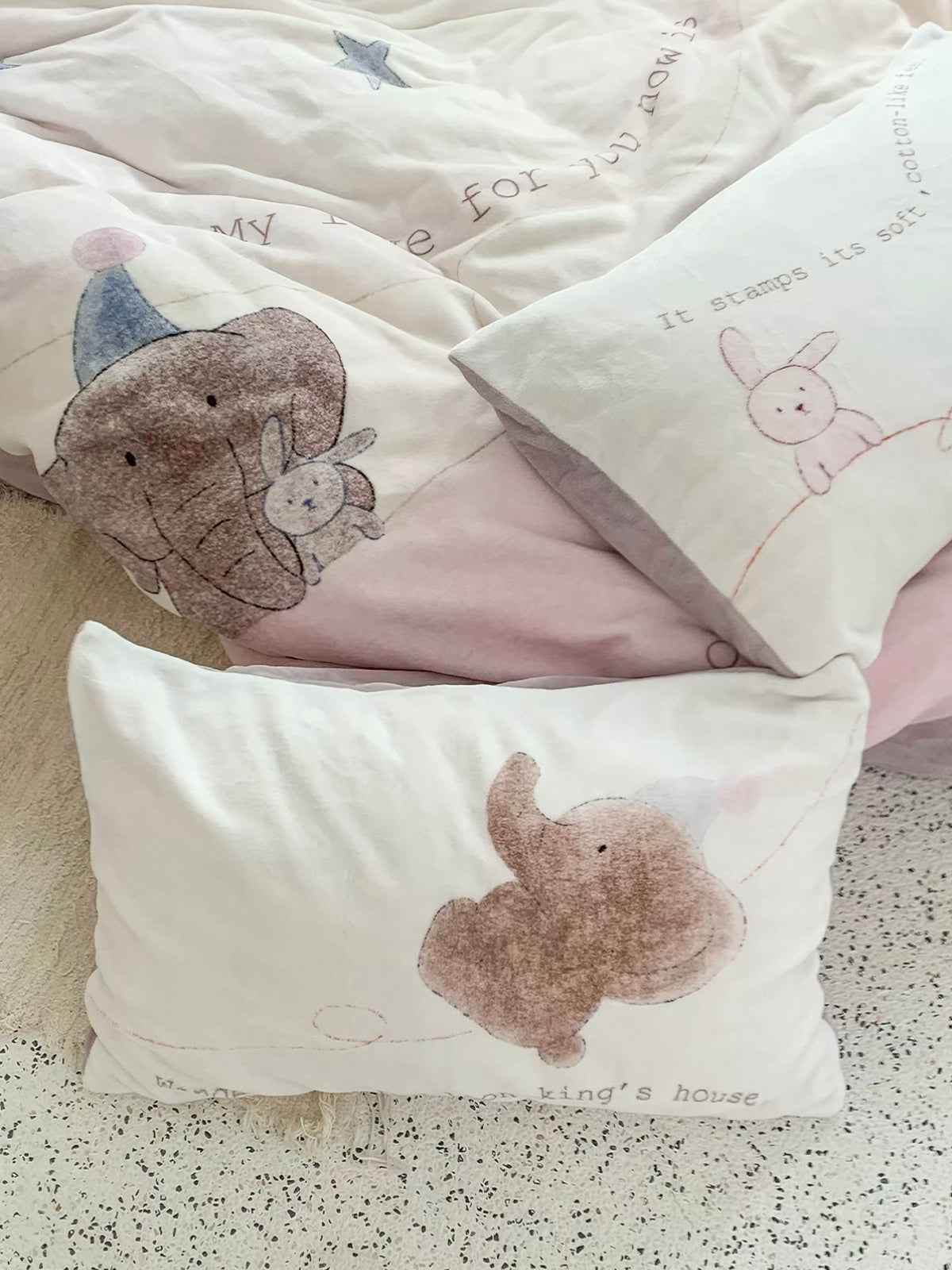 Elephant star bedding and illustrated pillowcases arranged in a woven basket.