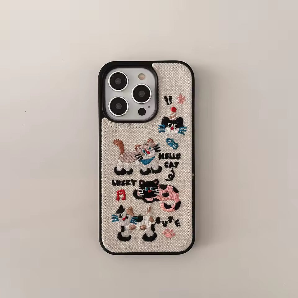 Phone case with embroidered cat designs on a beige background