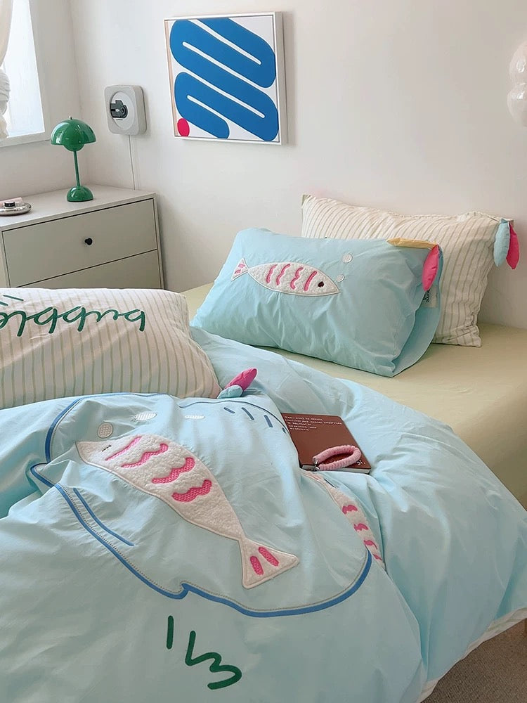 Cartoon fish embroidered cotton bedding styled with pastel decor and kawaii flower cushion.