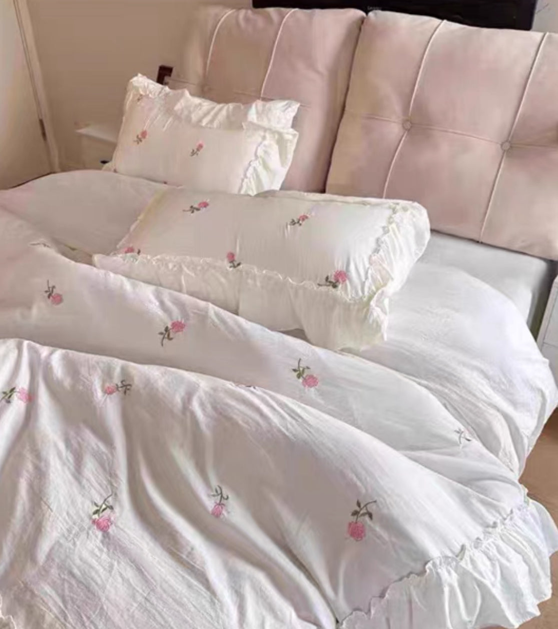 Embroidered rose pillowcases paired with a creamy white ruffle duvet cover