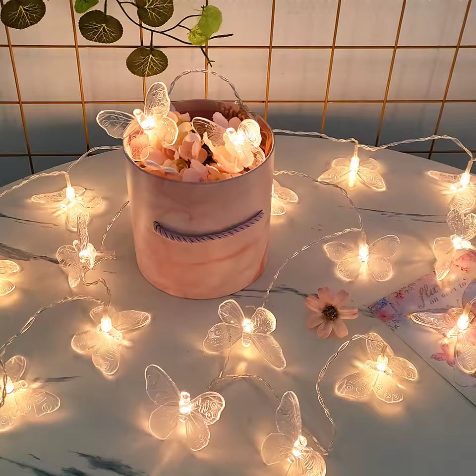 Butterfly string lights around a pink pot with flowers on a tiled wall background