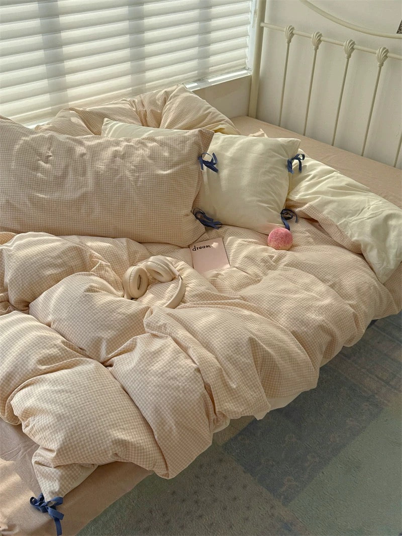Beige comforter and pillows on a bed with a window in the background