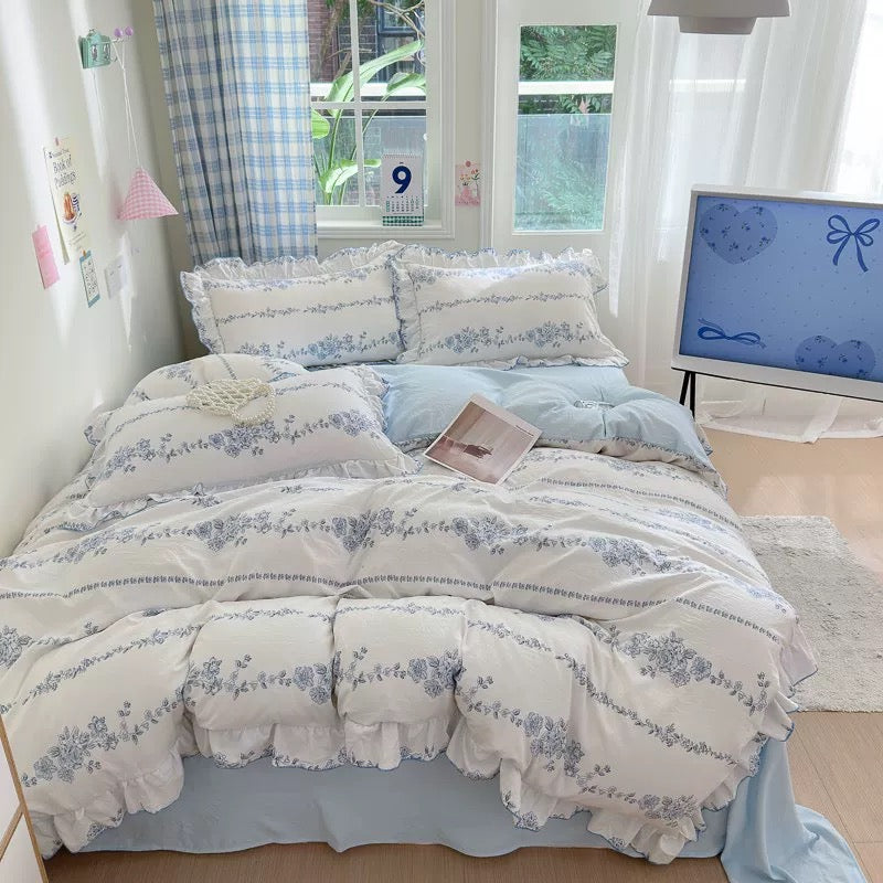 Floral patterned bedding set on a bed in a bright room with a calendar and TV in the background.