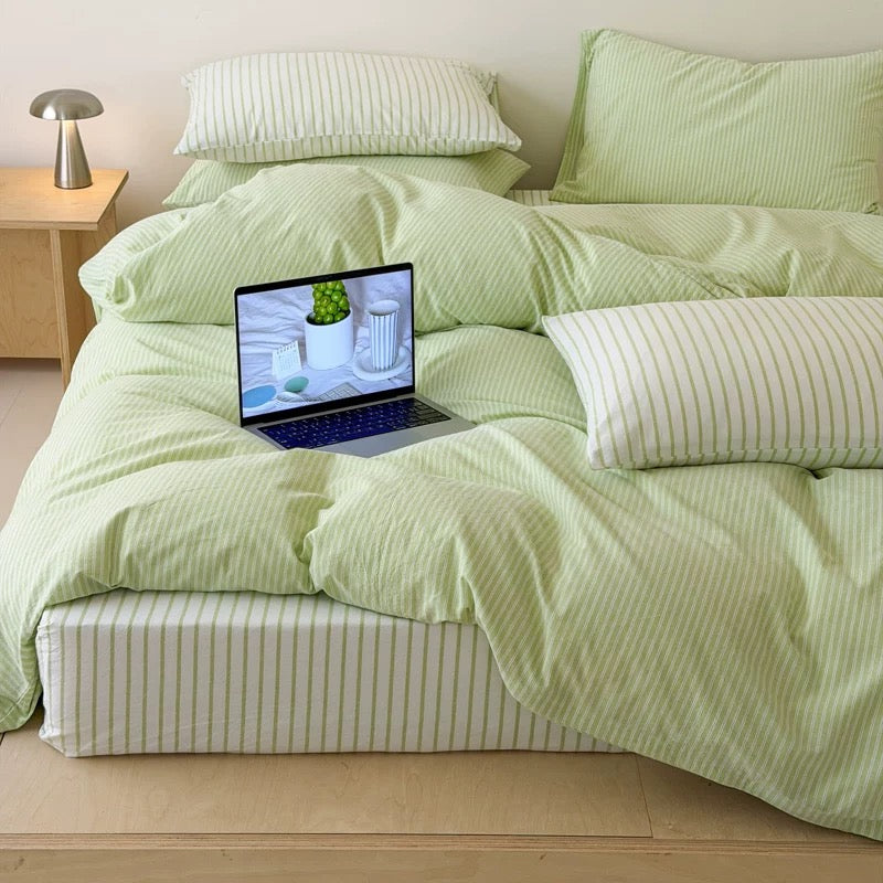 Cozy apartment sleep space decorated using fresh green cotton bedding and subtle thin striped textile pattern beautifully.