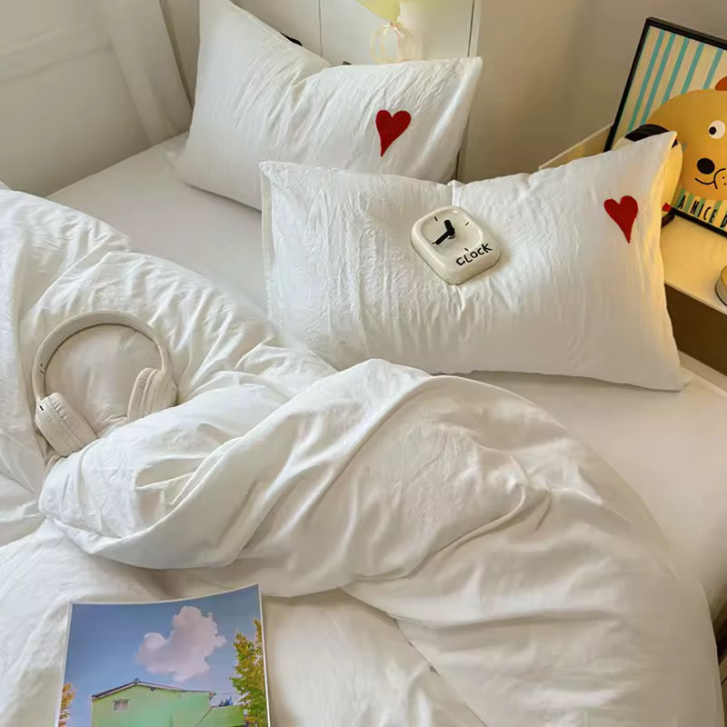 Queen size bed adorned with white heart bedding set and pastel room decor.