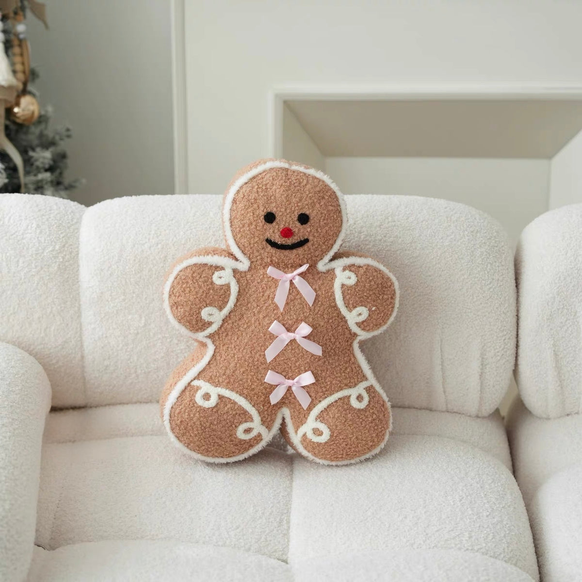 Gingerbread man pillow with pink bows and white icing details styled on a light-colored chair