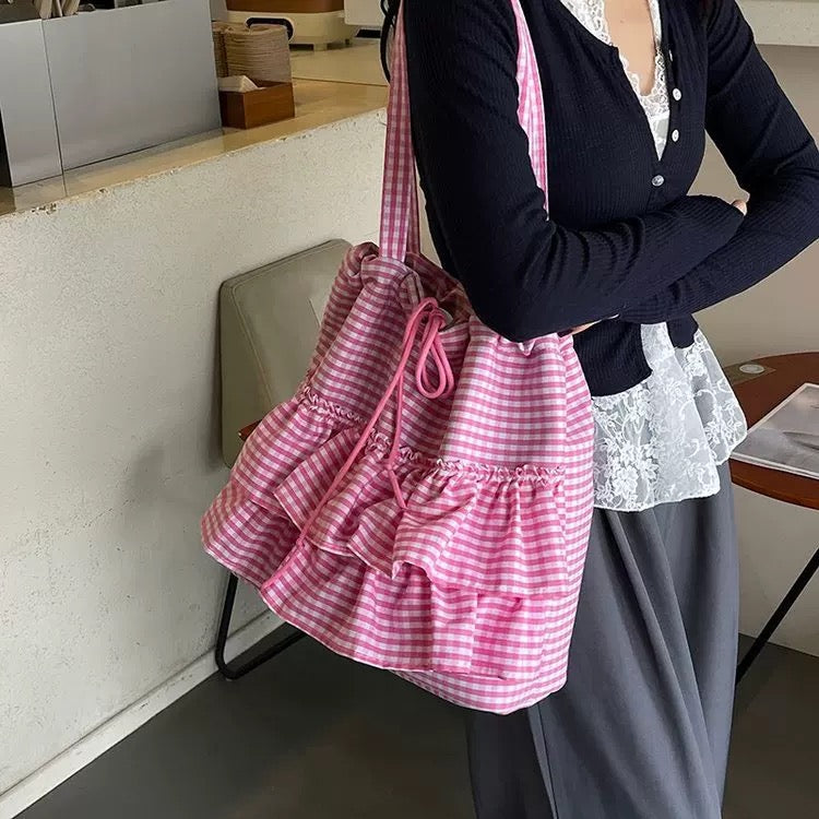 Person holding a pink and white checkered bag in an indoor setting