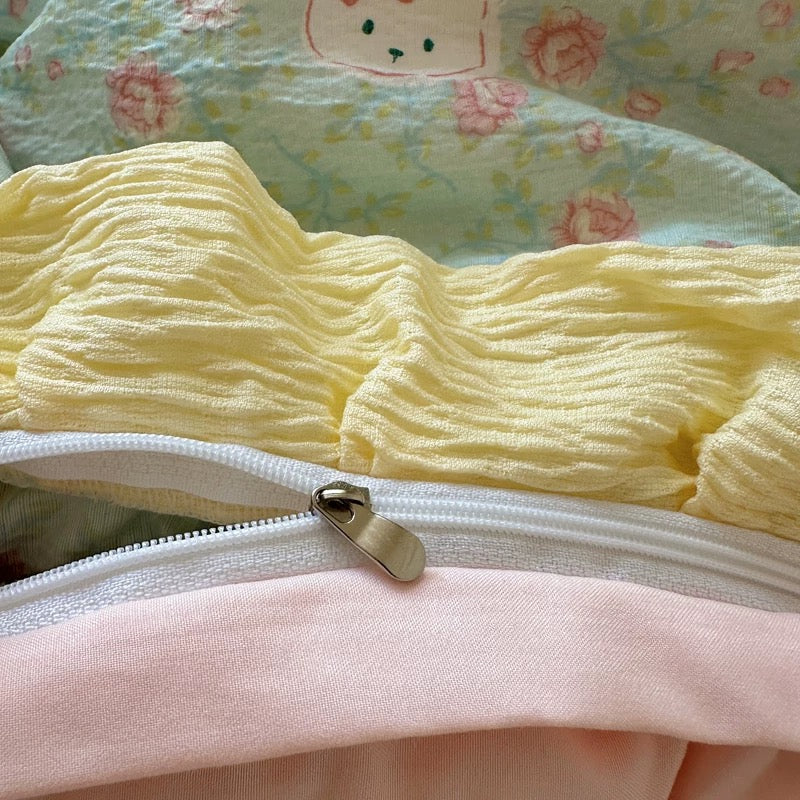 Embroidered bunny detail with a pink bow stitched onto a sage green floral pillowcase corner

