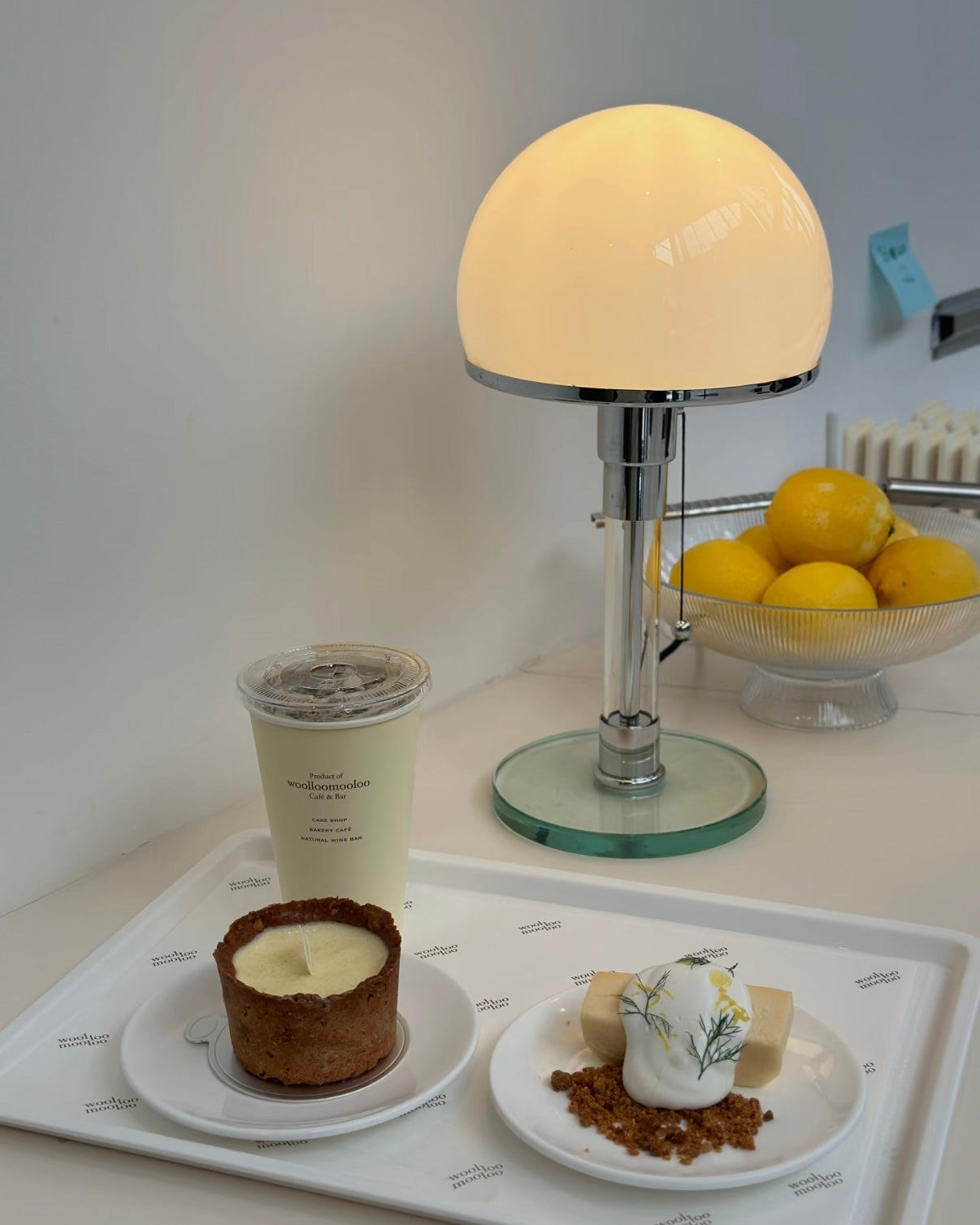 Y2K chrome accent lamp glowing softly on minimalist nightstand with white wall background decor.