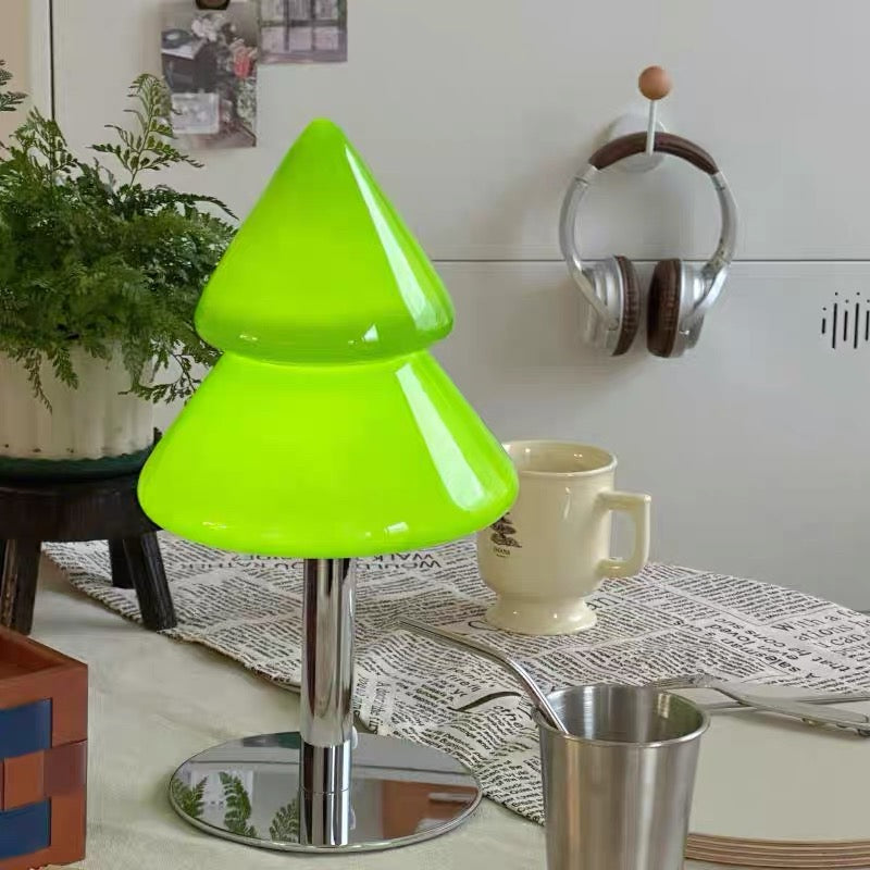 Green lamp shaped like a Christmas tree on a table with a mug and newspaper.