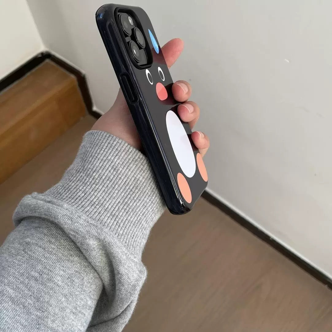 Hand holding a smartphone with a black case featuring cartoonish face design on a neutral background